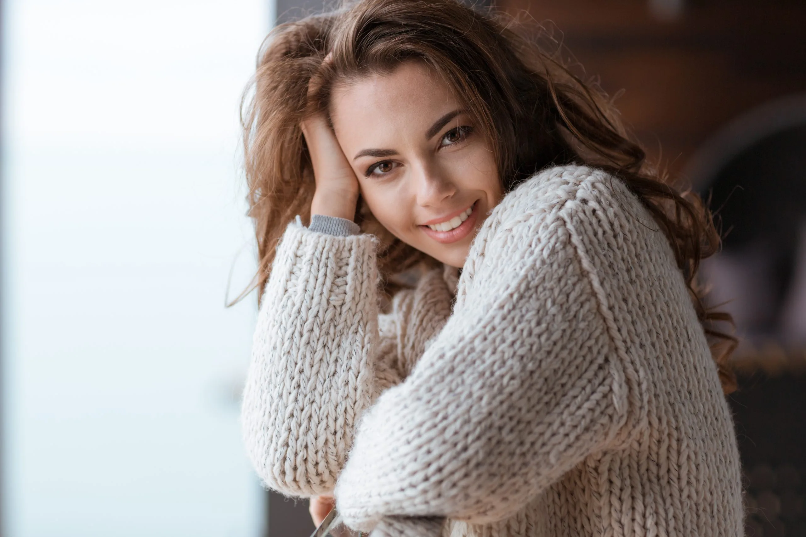 Smiling woman in a knit sweater, illustrating mental wellness