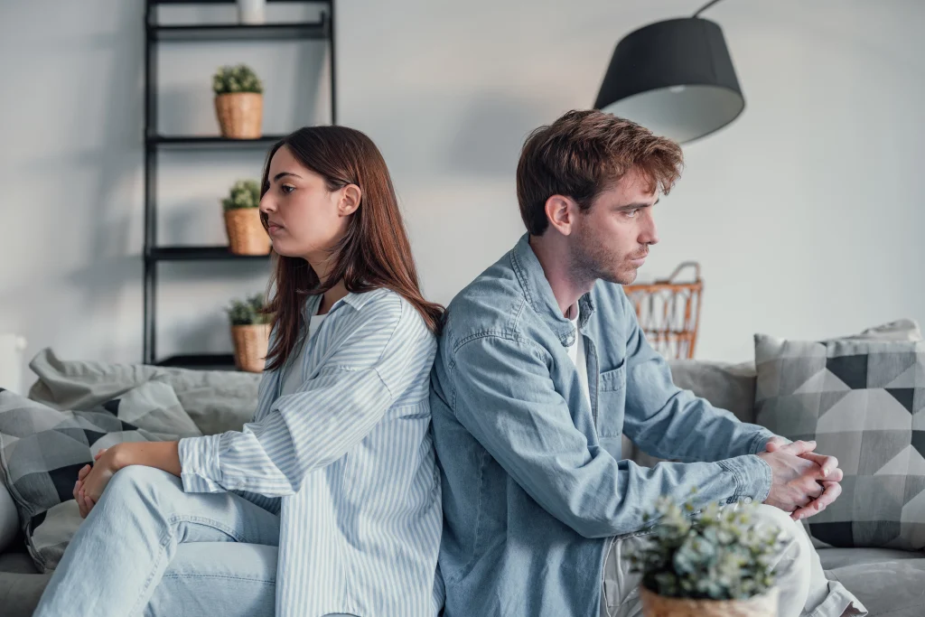 Couple sitting back to back on a sofa after an argument