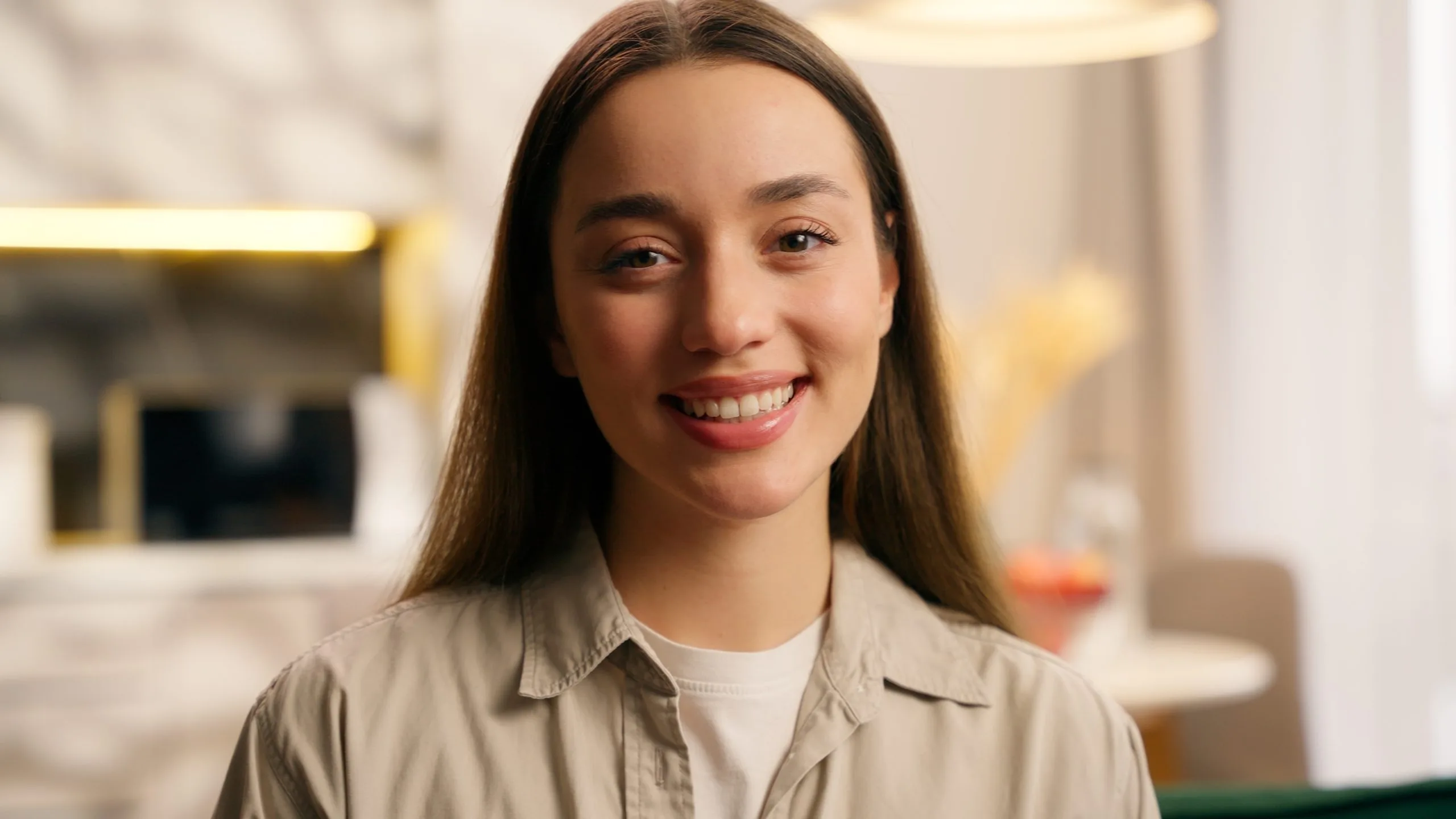 Smiling young woman with long brown hair in a softly lit indoor setting