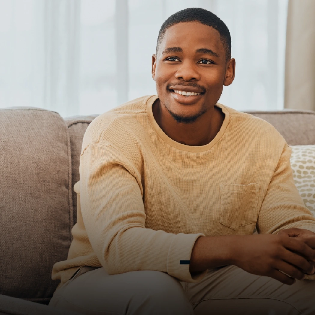 Smiling man sitting casually on a sofa in a bright living room