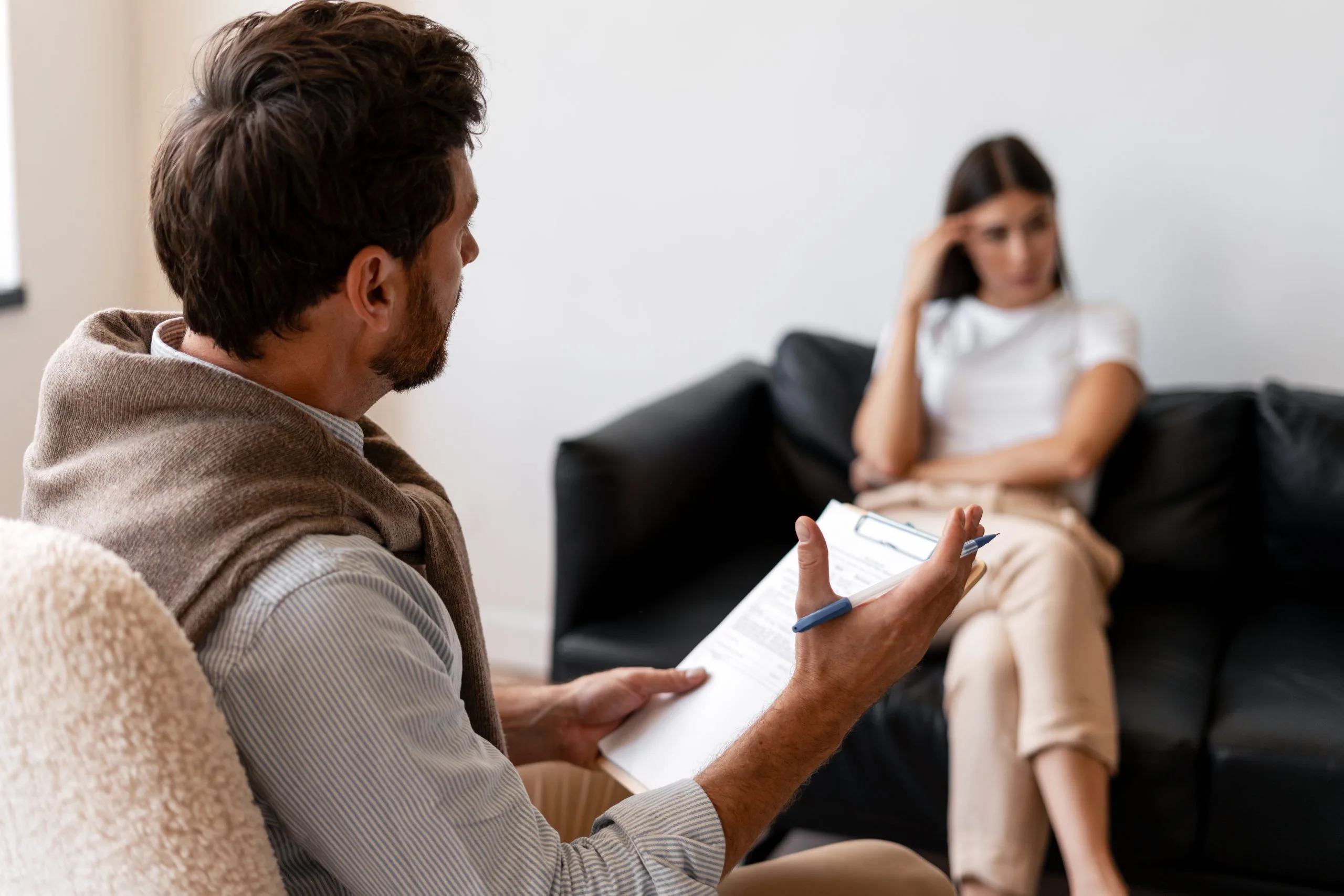 Therapist with a clipboard and a client on a couch