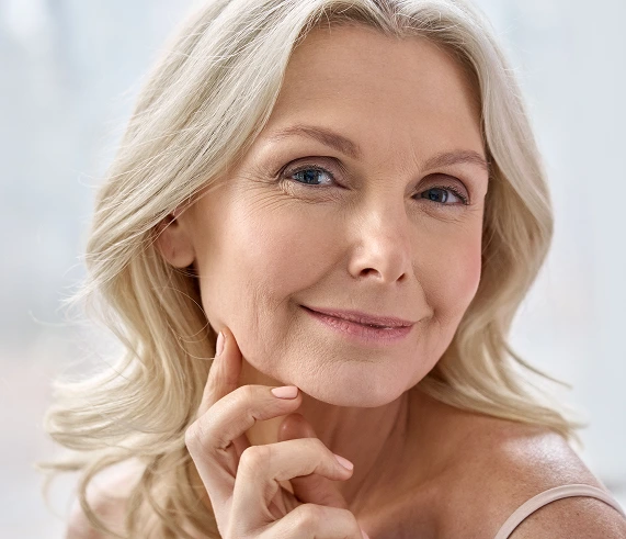 Woman with enhanced eyebrows and lashes demonstrating results of lash and brow services