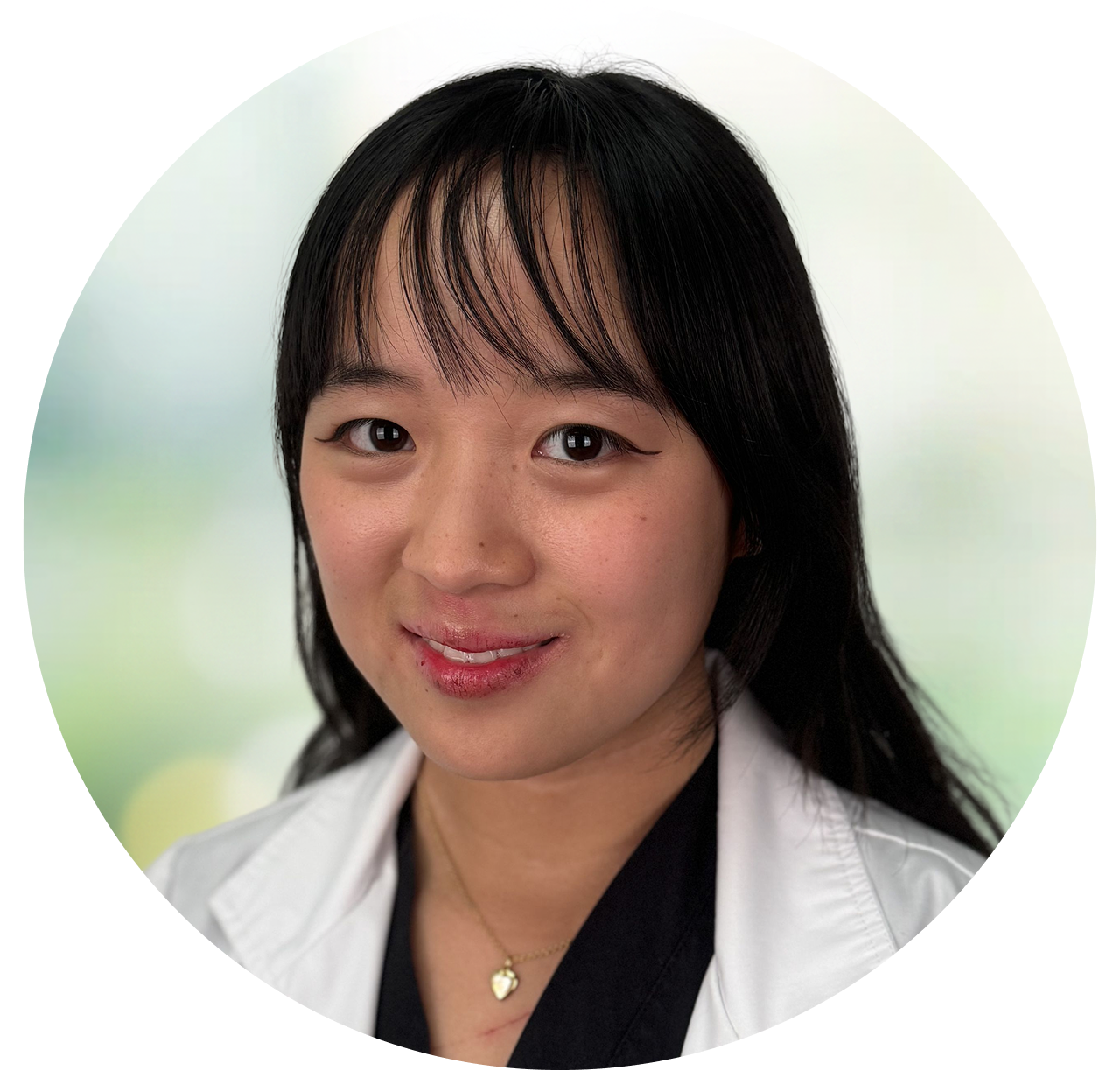 Professional headshot of woman with black hair and white coat against blurred green background