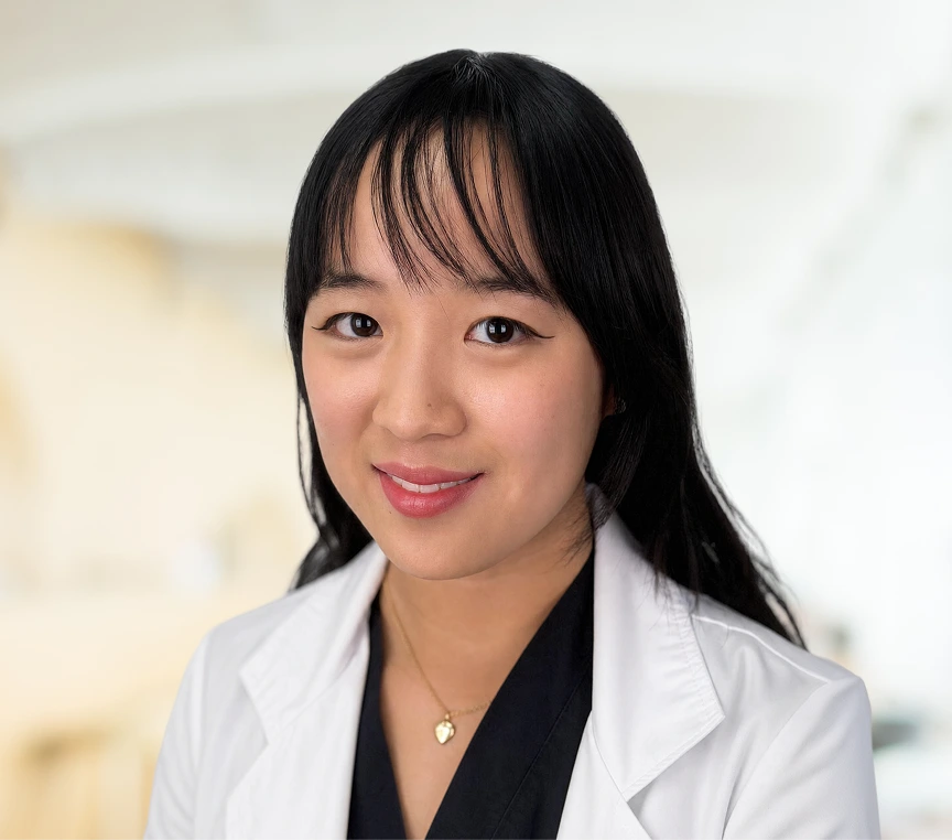 Team member wearing white medical coat smiling at camera