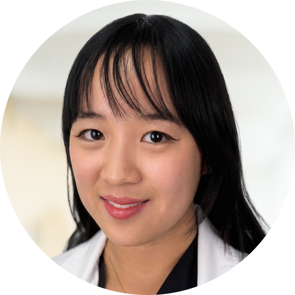 Professional headshot of a woman with black hair and bangs wearing a white and black jacket
