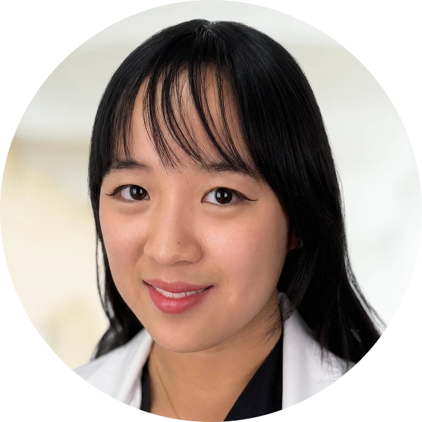 Professional headshot of a woman with black hair and bangs wearing a white and black jacket