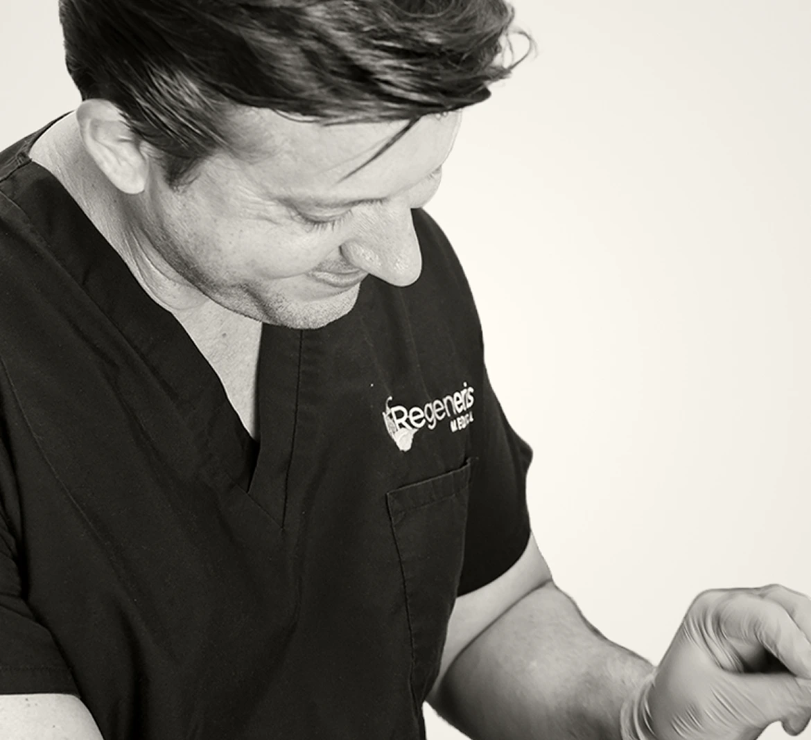 Regeneris Cosmetics clinician in black branded scrubs examining a patient's skin