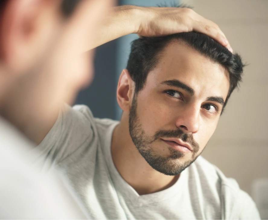 Man examining his hairline with hand in profile view