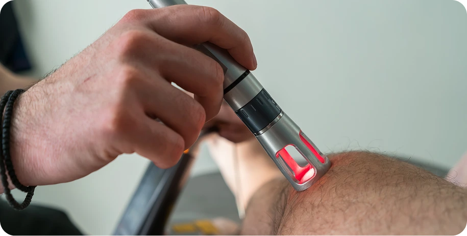 Practitioner applying low-level laser therapy to a patient's foot with a handheld laser device