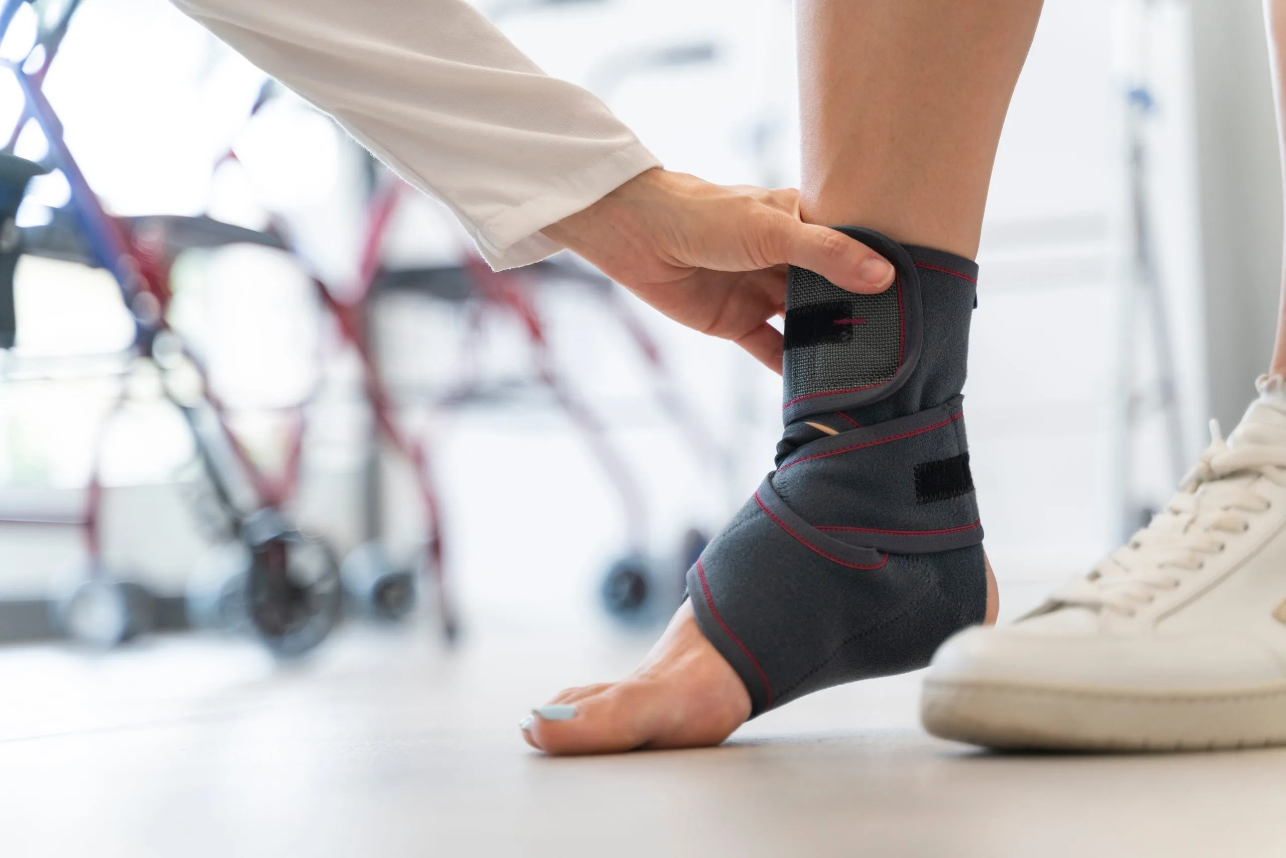 Healthcare provider fitting a black and red compression ankle brace on a patient's foot
