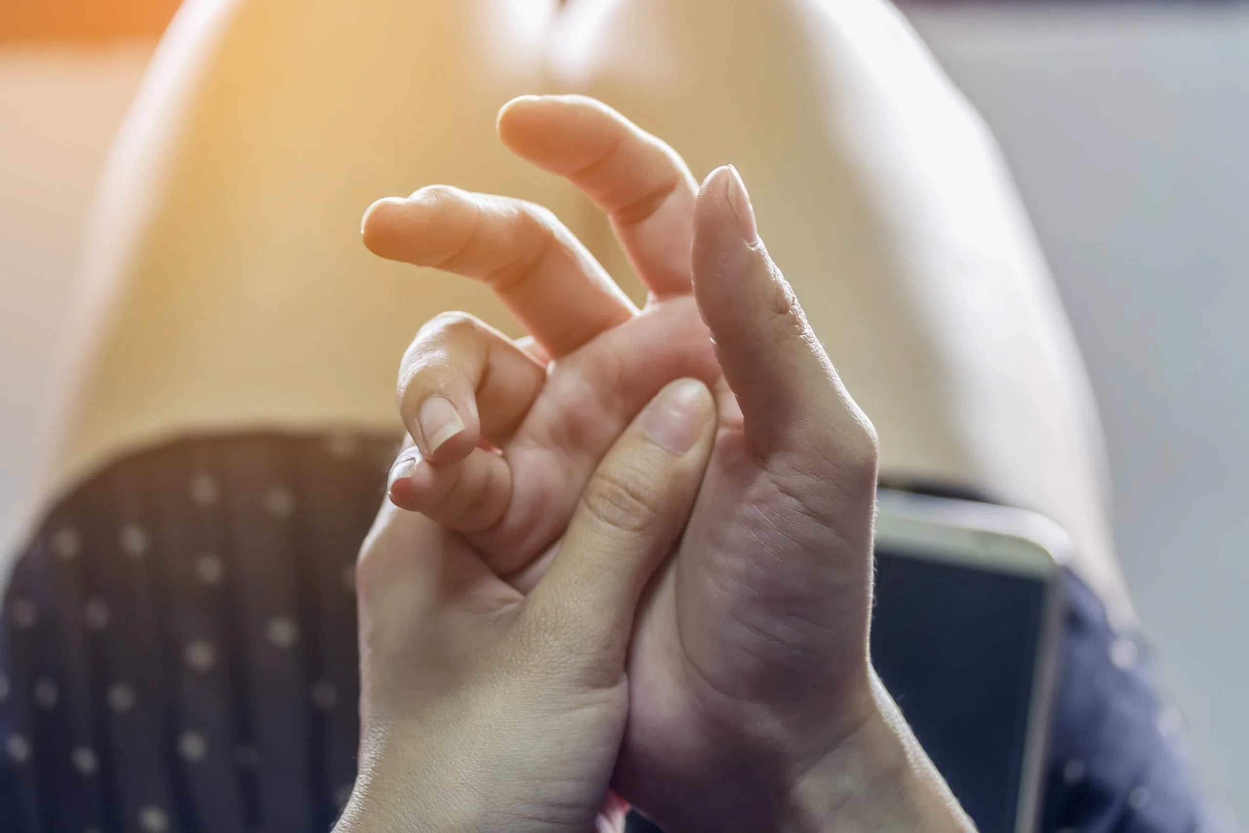 Adult hand gently holding a child's hand, showing care and support
