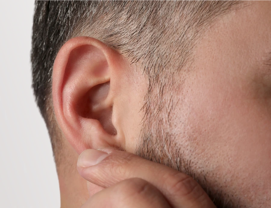 Close-up of man's ear and surrounding facial area with short dark hair