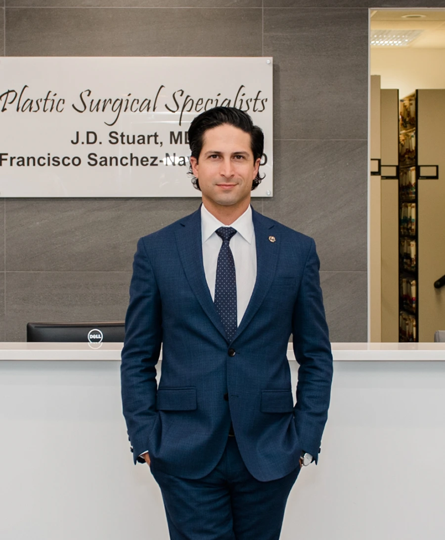 Dr. Francisco Sanchez-Navarro in dark suit standing at clinic reception desk