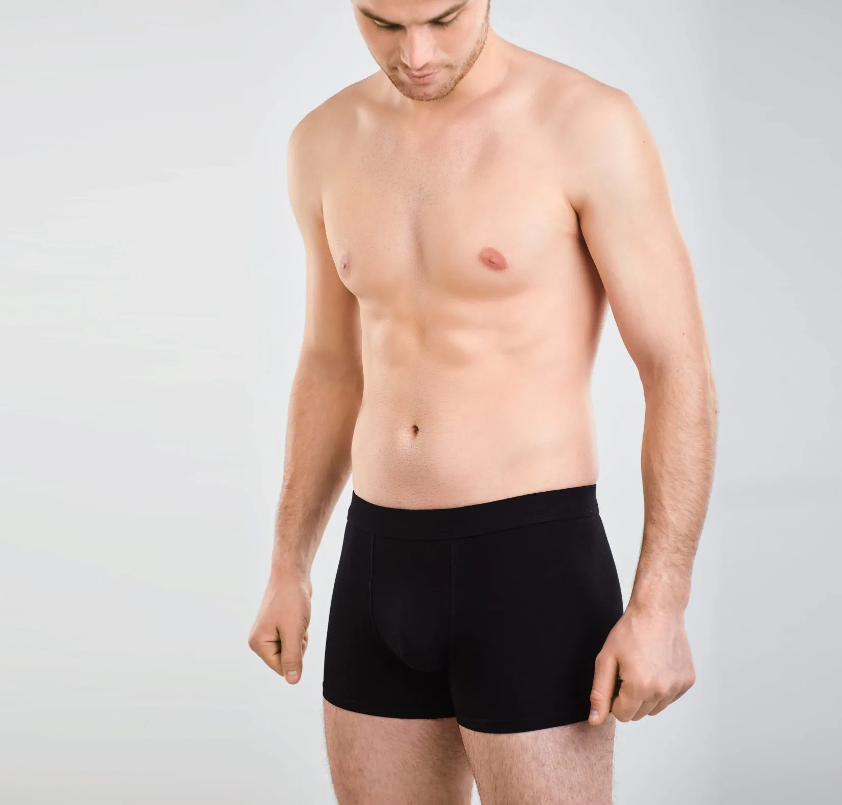 Man in black underwear standing against a gray background