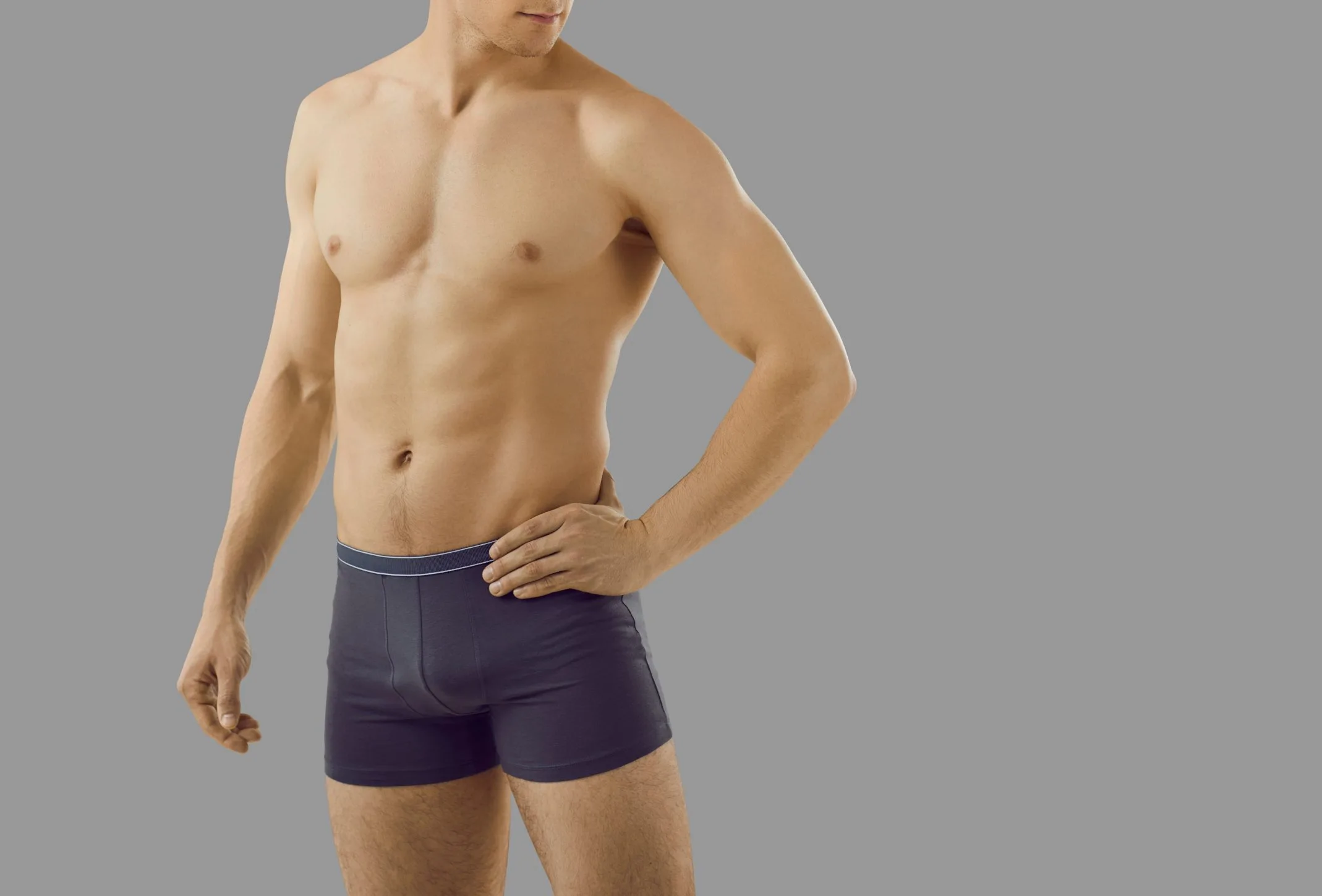 Shirtless male model in dark underwear against neutral background