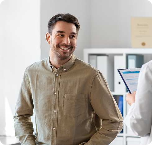 Man in tan button-up shirt smiling in a bright medical office setting