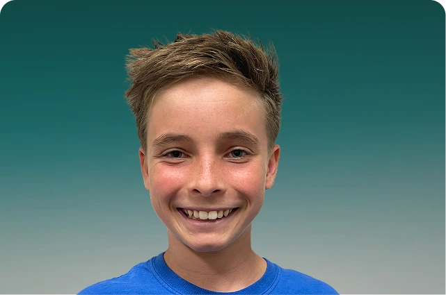 Smiling young person in blue shirt against teal background
