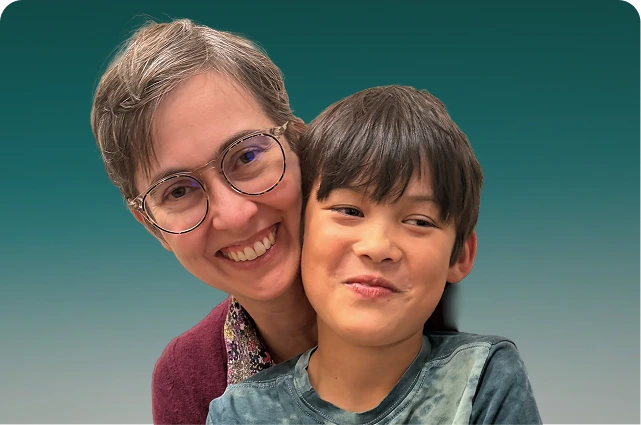 Adult and child smiling together against a teal background