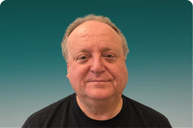 Headshot of a man with gray hair wearing a black shirt against a teal gradient background
