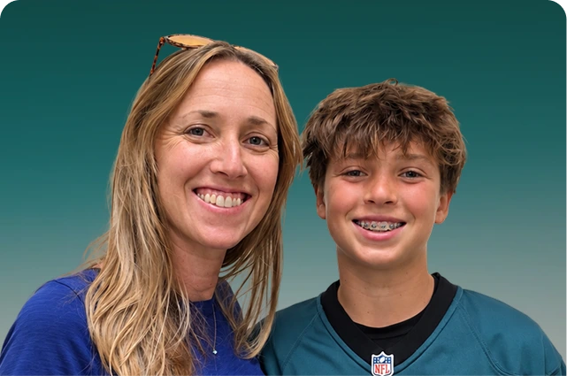 Woman and boy smiling together against a teal background