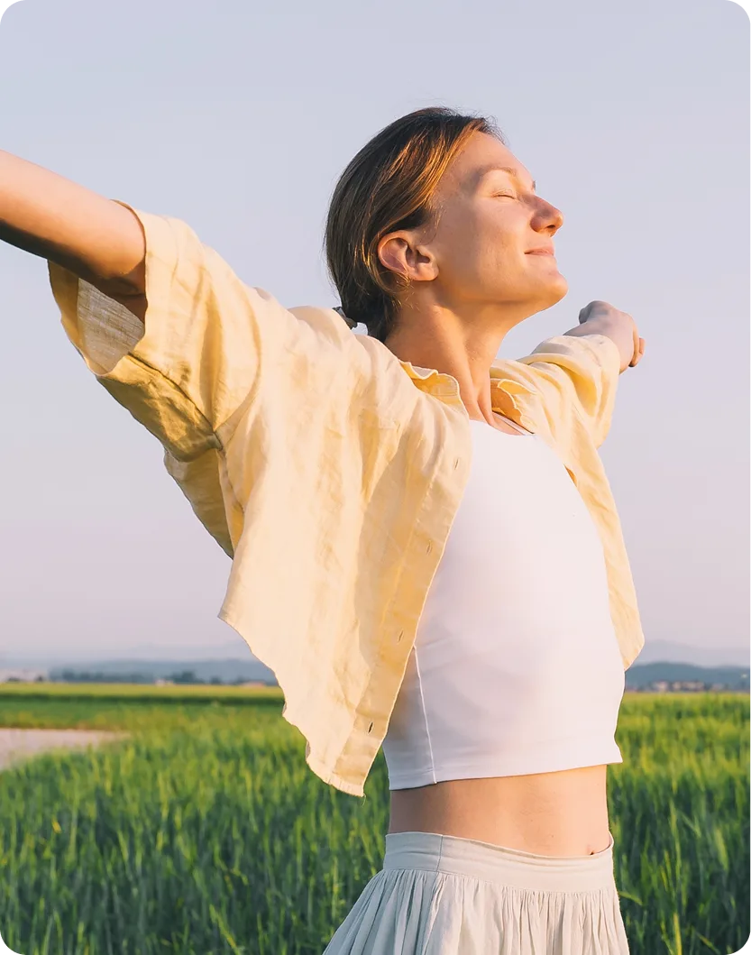 Woman with arms outstretched enjoying relief in an open green field