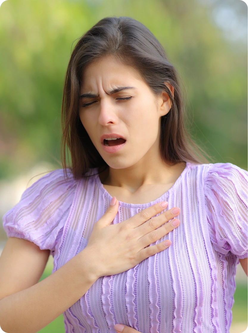 Woman outdoors coughing with hand on chest, demonstrating a symptom of occupational asthma