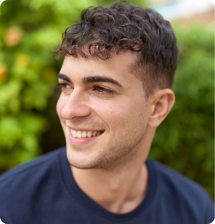 Man smiling outdoors with green foliage background
