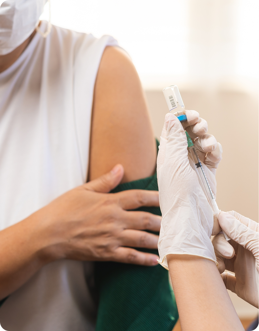 Healthcare provider in white gloves preparing an injection for patient's upper arm