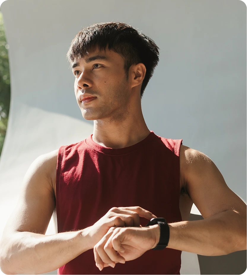 Athletic man in red shirt checking fitness watch, representing exercise-induced asthma prevention