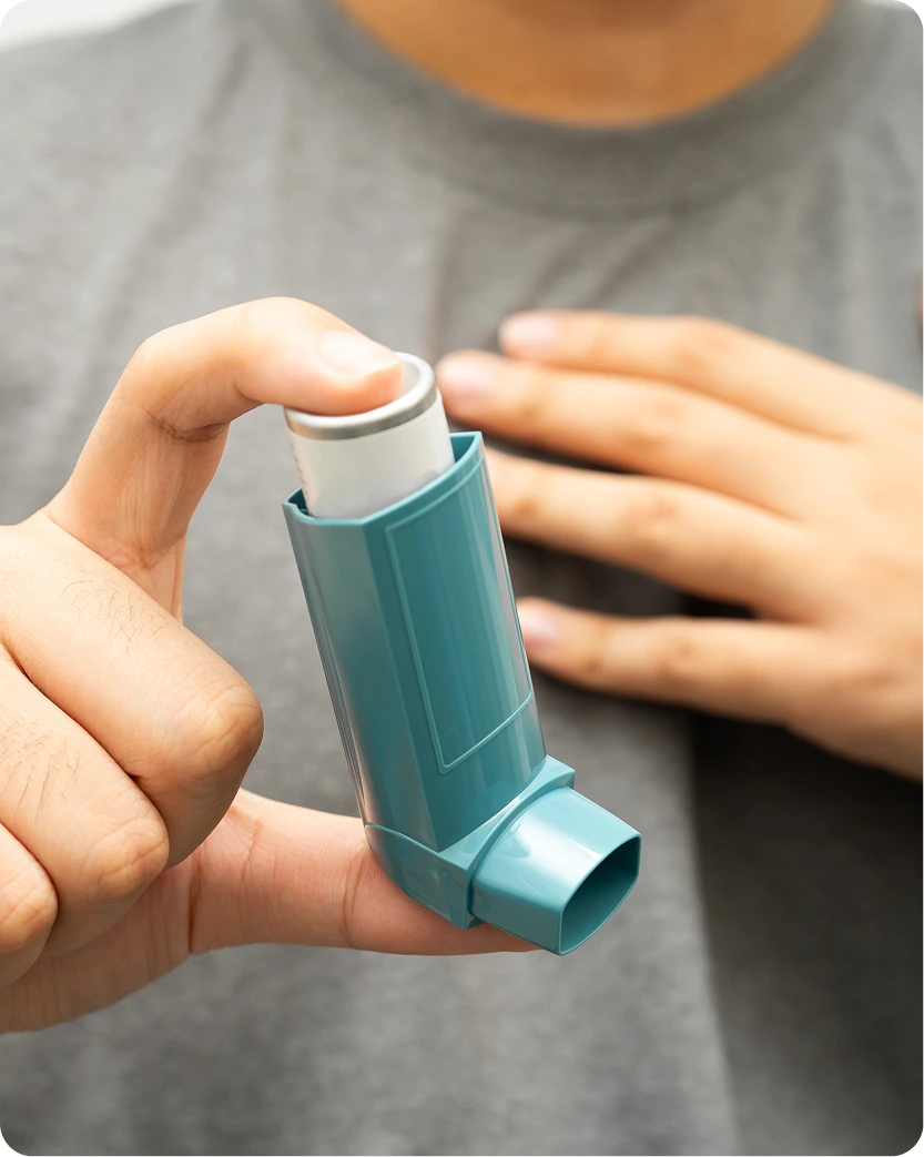 Person holding a teal asthma inhaler with hand positioned to use it
