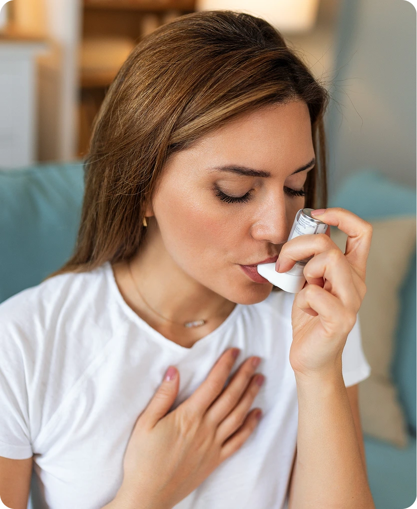 Woman using a rescue inhaler while experiencing chest discomfort