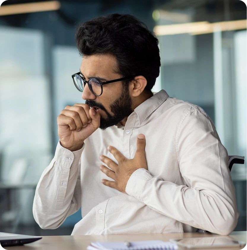 Man in office coughing into his fist, illustrating occupational asthma symptoms