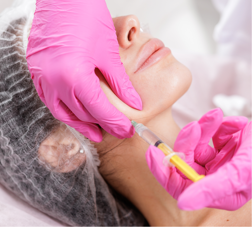 Practitioner in pink gloves administering jawline filler injection to patient's chin and lower face