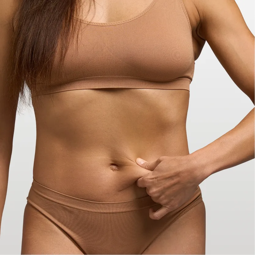 Woman touching her abdomen demonstrating flat, toned midsection