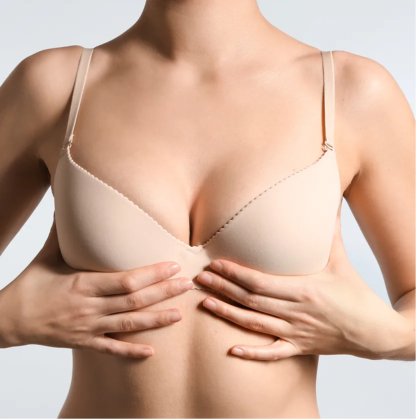 Woman in beige bra with hands on chest, marked surgical guidelines visible
