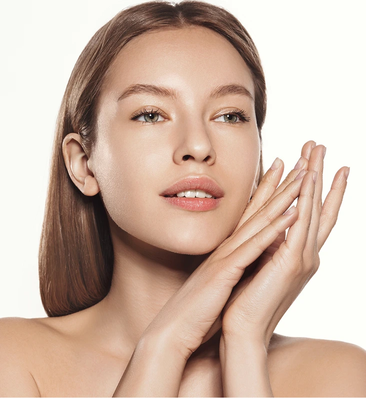 Woman with clear skin touching her face with both hands against a white background