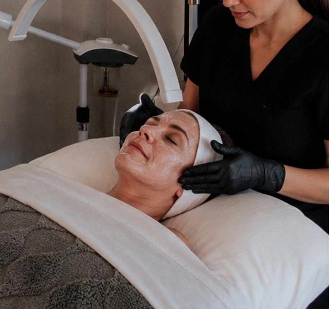 Esthetician applying a customized facial treatment to a relaxed patient in a clinical treatment room