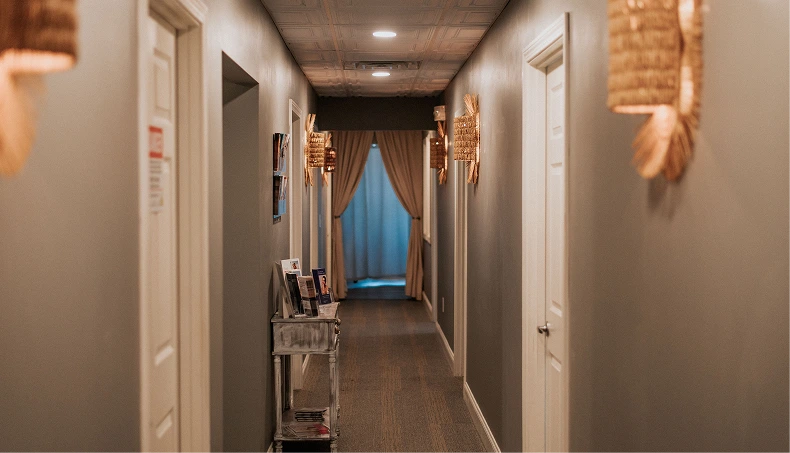Spa hallway with white doors, brown curtains, pendant lighting, and beige walls