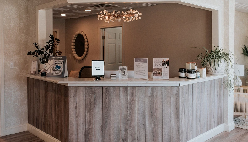 Curved reception desk with wood paneling, product displays, decorative mirror, and potted plant