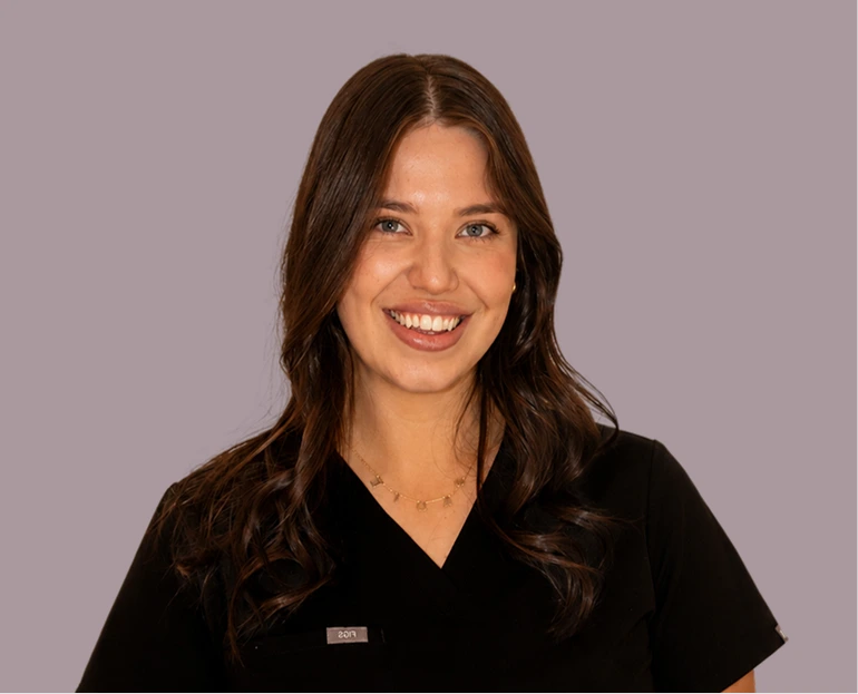 Dr. Lauren Moore, woman with long dark hair wearing black scrubs, smiling at camera