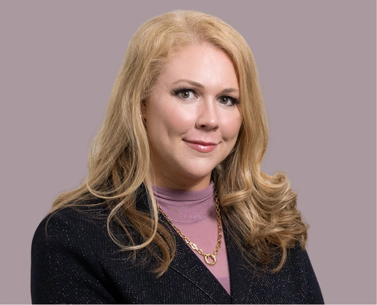 Dr. Lauren Moore, blonde woman wearing purple turtleneck and dark blazer against purple background