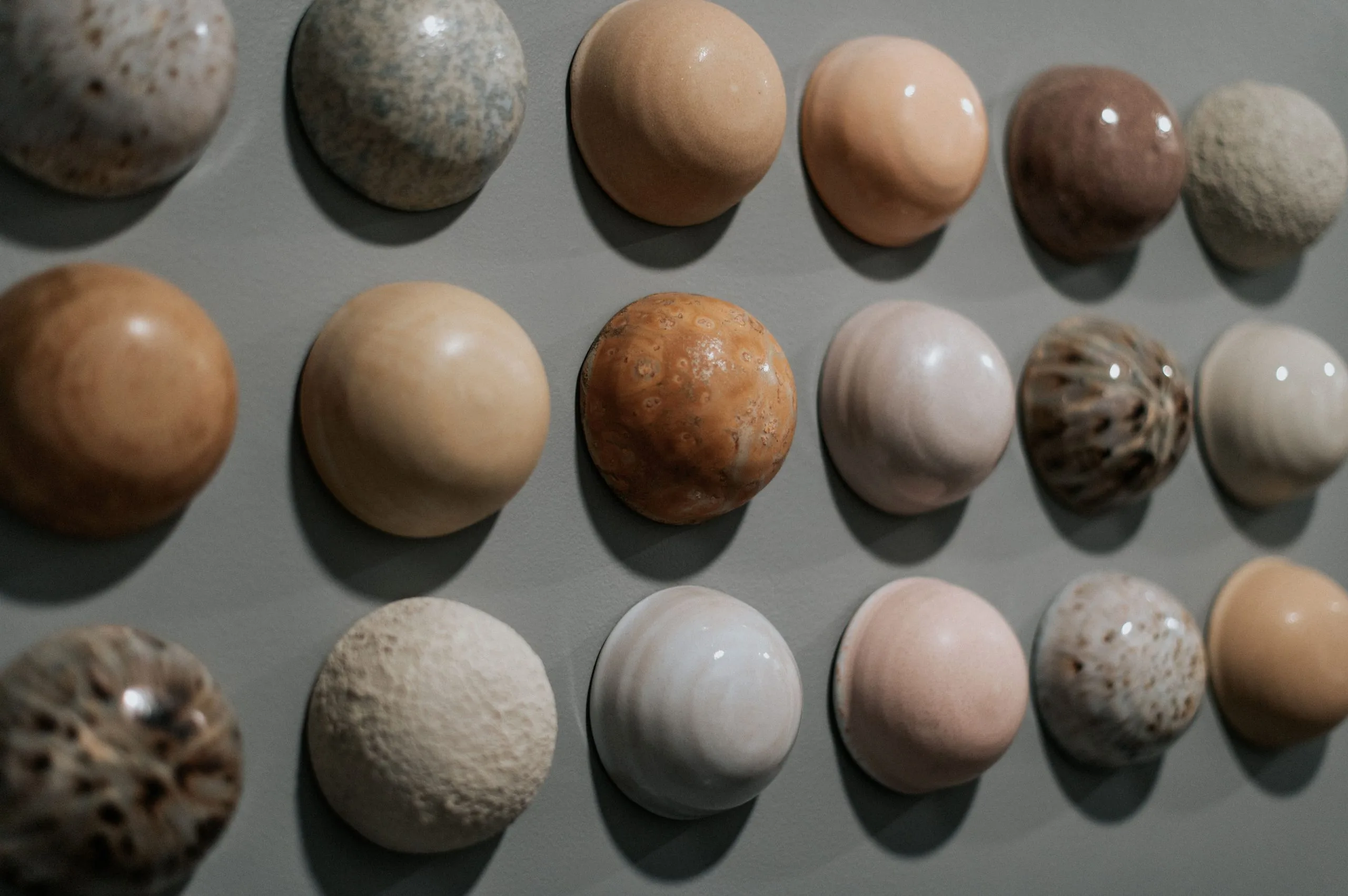 Collection of polished hot stones in various earth tones and textures used for hot stone massage therapy