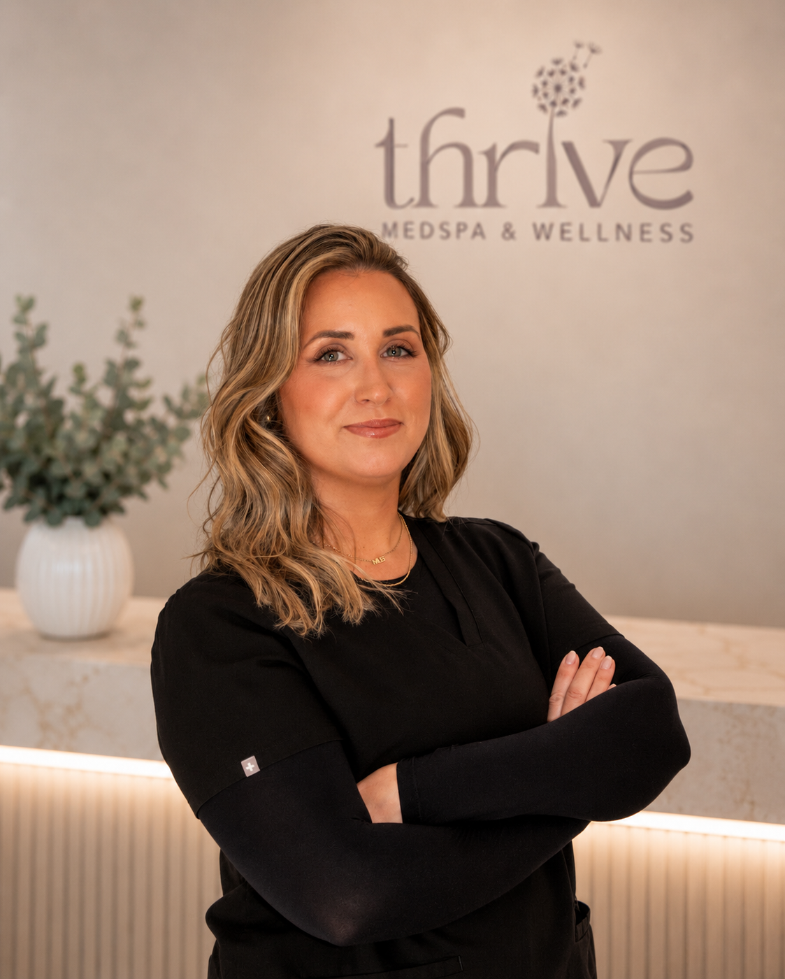 Emily T Tarr standing with crossed arms at Thrive Med Spa + Wellness reception area