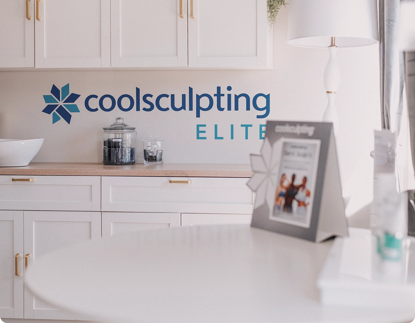 CoolSculpting Elite logo and branding on a spa treatment room wall with white cabinetry and countertop