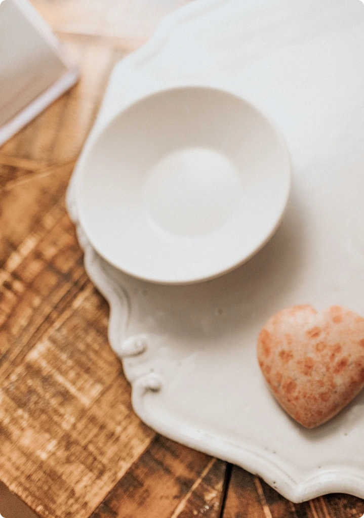 White ceramic bowl with cream and heart-shaped cookie on woven placemat