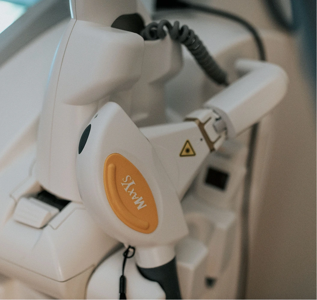 SXW IPL treatment device with orange button and black handpiece in clinical setting