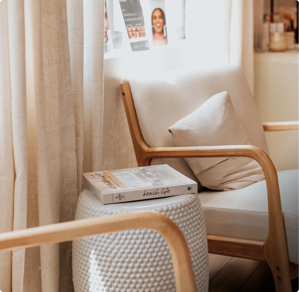 Serene spa waiting area with wooden chairs, cream pillows, and patient photos pinned on a wall