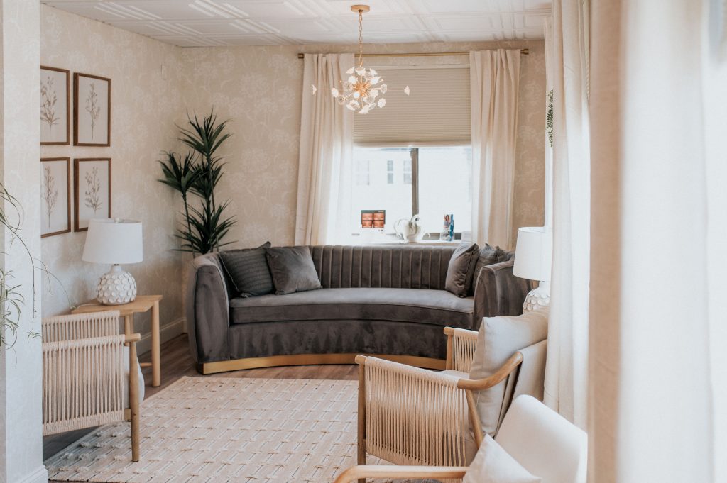 Spa waiting room with curved gray sofa, wooden chairs, potted plant, and pendant lighting overlooking Portsmouth street