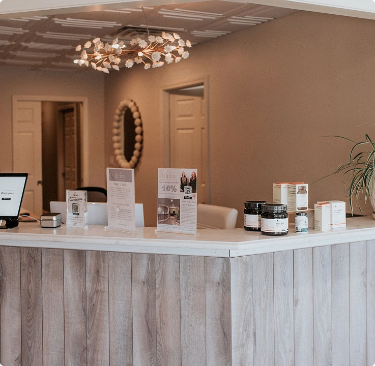 Thrive Med Spa reception desk with product displays, informational brochures, and a decorative pendant light fixture
