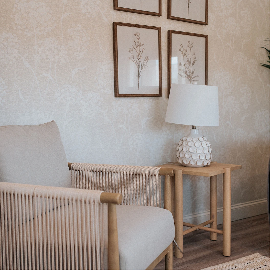 Serene waiting area with neutral chairs, wooden side table with ceramic lamp, and botanical wall art